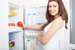Mujer sacando una manzana de un refrigerador